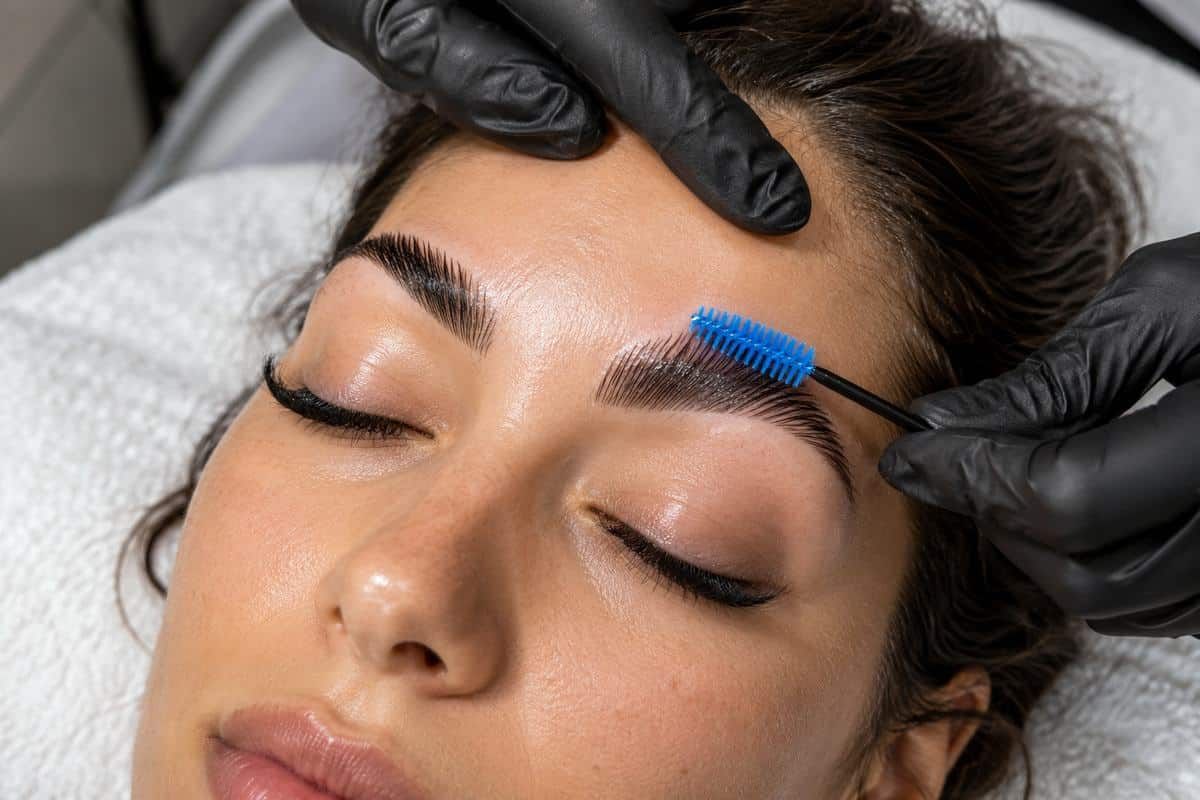 Brow specialist brushing laminated brows into place