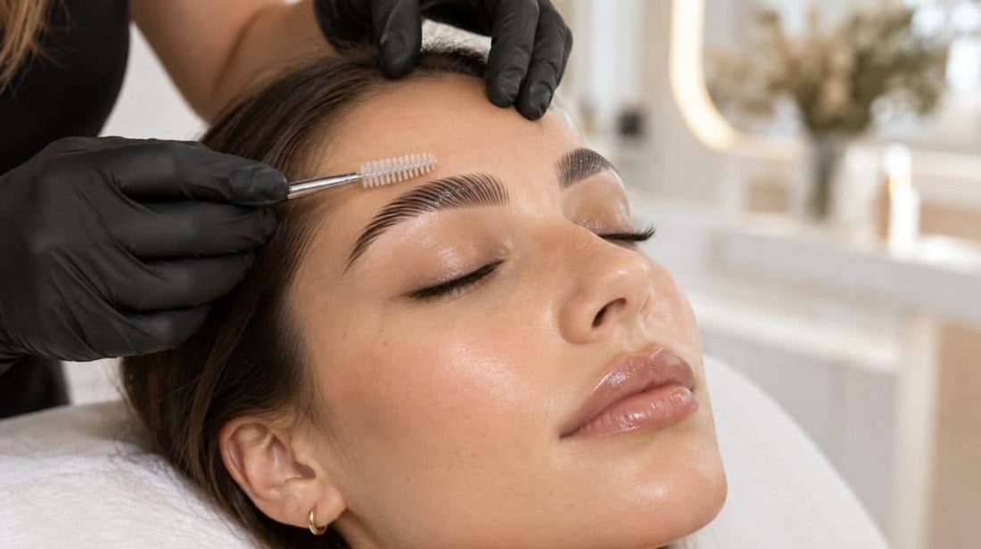 Artist combing a client's brows with a spoolie
