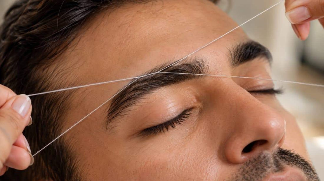 Close-up of a man's eyebrows being threaded