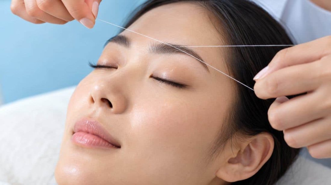 East Asian woman relaxing during eyebrow threading