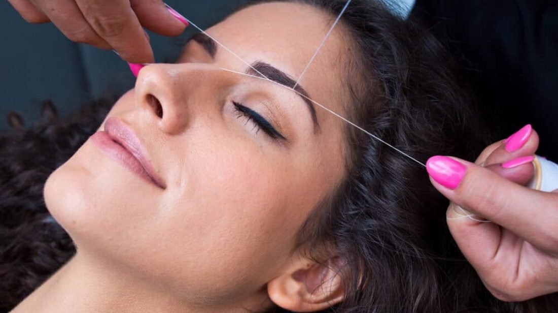women getting an eyebrow threading